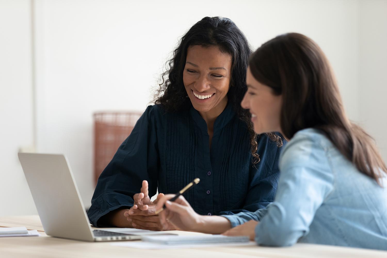 Woman helping another woman use a laptop