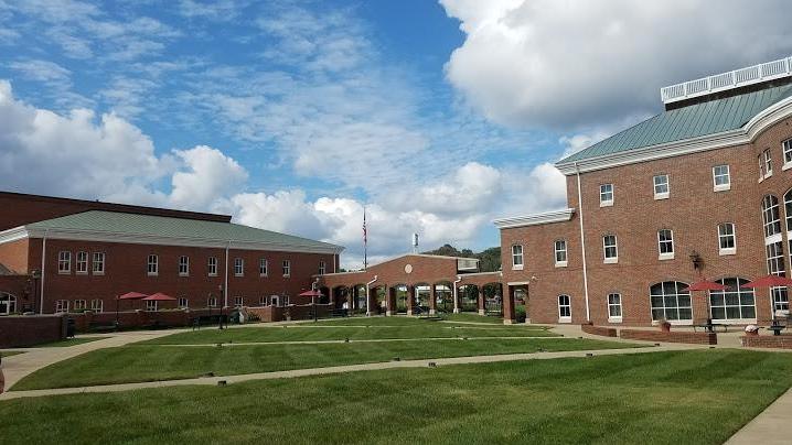 A courtyard with green grass surrounded by brick buildings