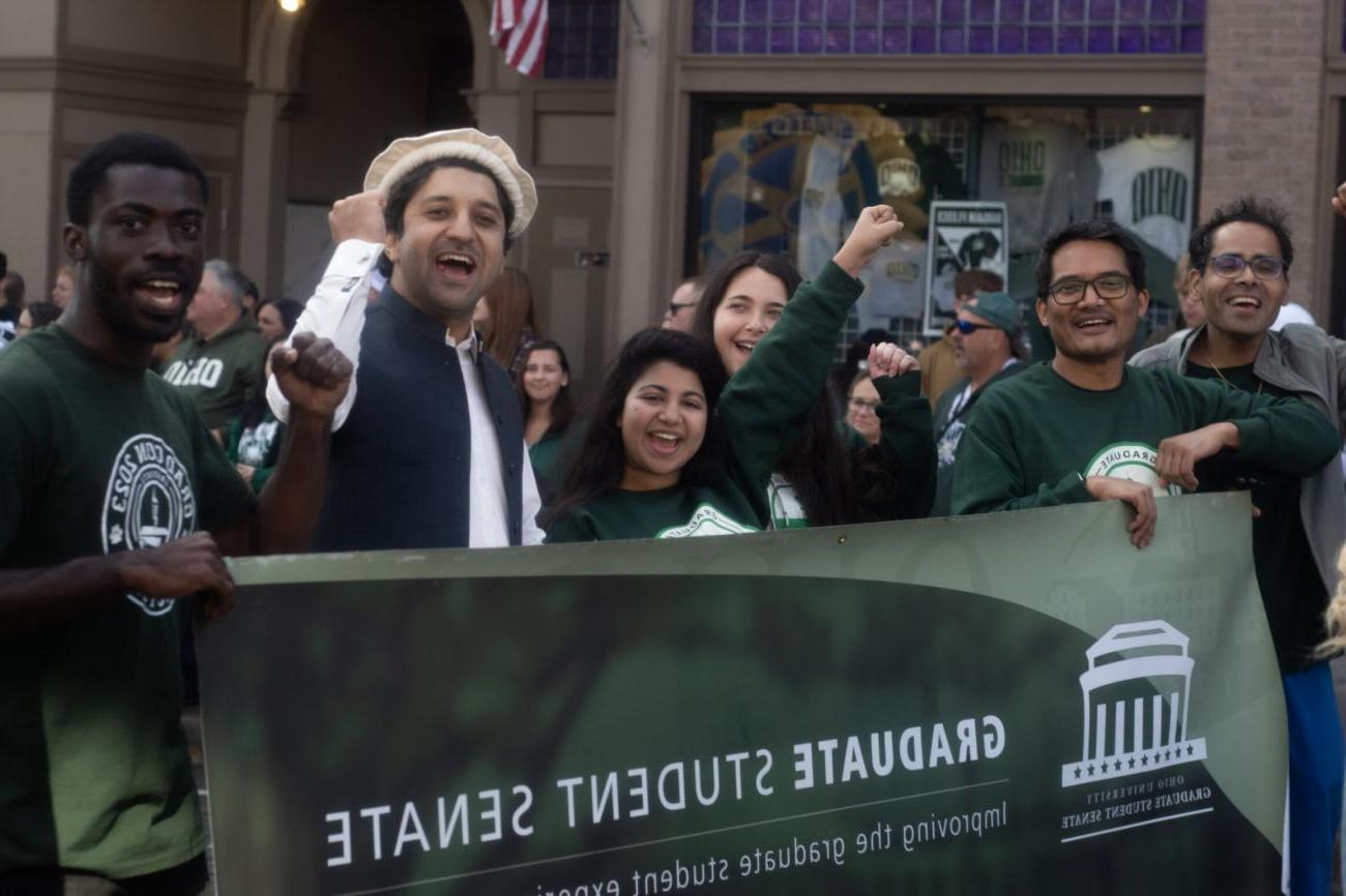 A group of graduate students behind a Graduate Student Senate banner