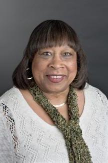 Headshot of woman in white sweater with green scarf.